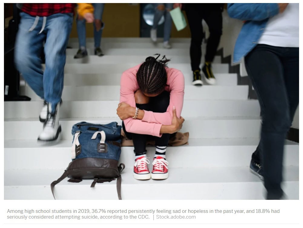 Youth sits on stairs and holds knees