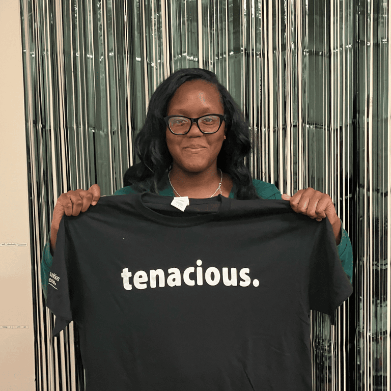 Tenacity Award winner holds up "tenacious" T-shirt