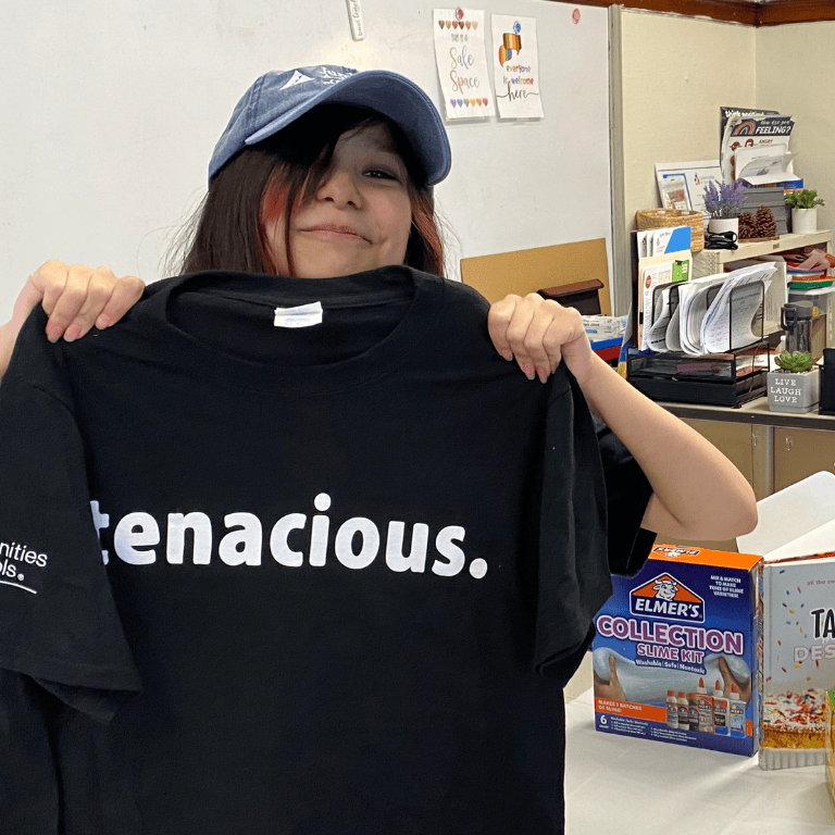 Tenacity Award winner holds up "tenacious" T-shirt