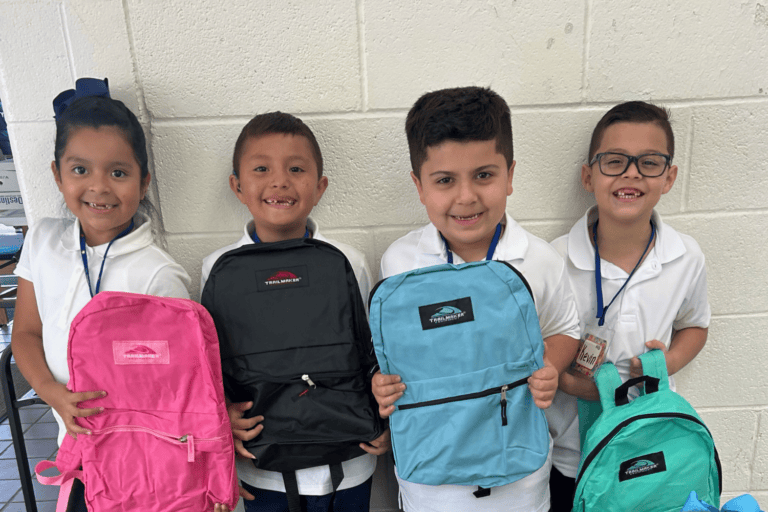 Elementary students hold backpacks